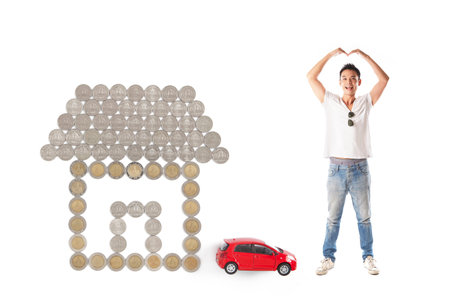 Happy asian man with coins in house shape and red car on backgroundの写真素材