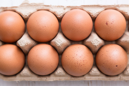 Eggs in paper container on white wooden table