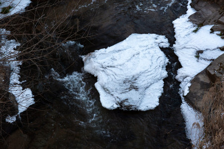 Aerial view of a small mountain river covered with ice and snow