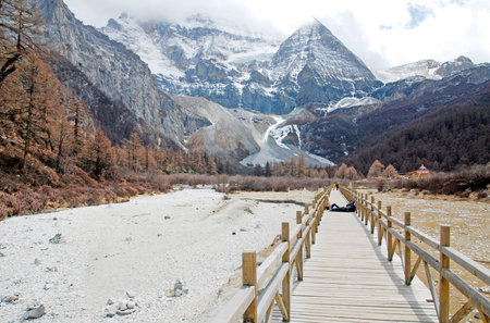 Long wood bridge to Pearl Lake with landscape Holy snow Mountain at Yading winter season in Daocheng...