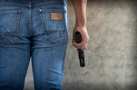 Killer man wears blue jeans with gun close up background with copyspaceの写真素材