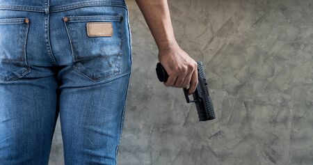 Killer man wears blue jeans with gun close up background with copyspaceの写真素材