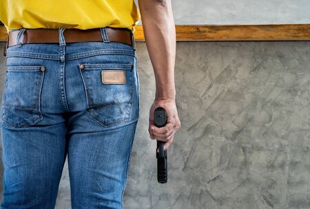 Killer man wears blue jeans with gun close up background with copyspaceの写真素材