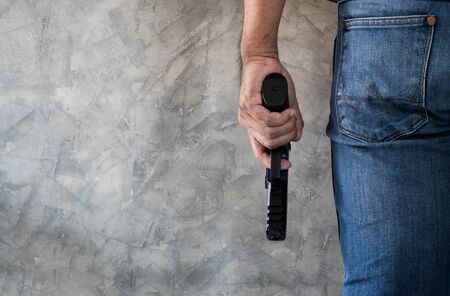 Killer man wears blue jeans with gun close up background with copyspaceの写真素材