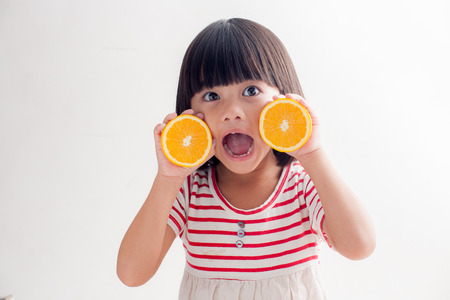 Little girl playing with orange fruitsの写真素材