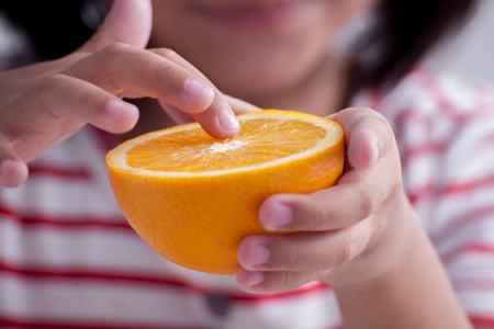 Little girl playing with orange fruitsの写真素材