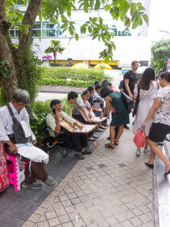 Silom BANGKOK,THAILAND-16 AUGUST 2018:  In the morning, people are walking to work and doing activities such as buying coffee to buy or shopping for lottery tickets, and queuing for a motorcycle.のeditorial素材