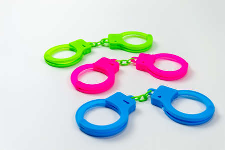 The toy handcuffs are available in green, pink and blue. On a white background.の写真素材