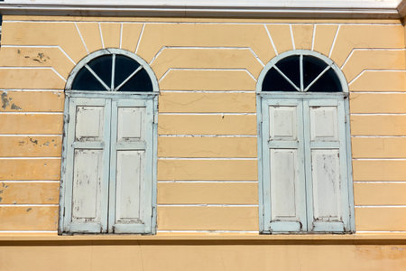 Two windows on a yellow wall in the city of Athens, Greece