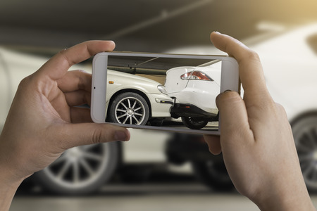 woman photographing his vehicle with damages for accident insurance with smart phone. The accident at the car parkの写真素材