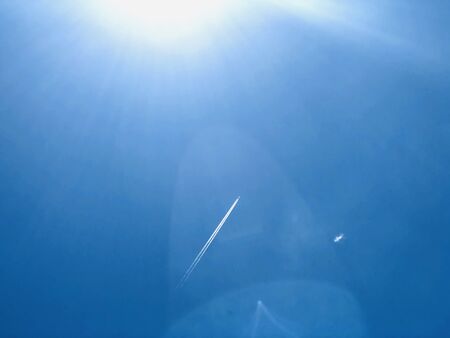 Blue sky and light from the sun and smoke from the planeの写真素材