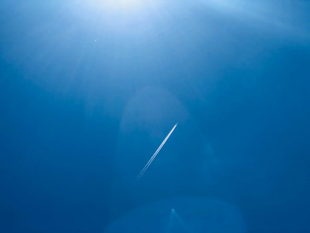 Blue sky and light from the sun and smoke from the plane