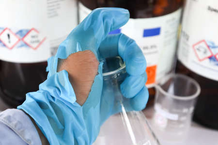 Use torn gloves when working with hazardous chemical in the laboratory or industryの写真素材