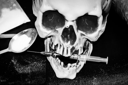 Heroin liquid and heroin powder on a skull background, concept of a narcotic substanceの写真素材