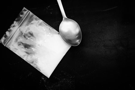 spoon and heroin powder on a black background, concept of a narcotic substanceの写真素材