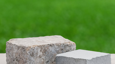 Empty stone podium on green grass background with copy space for product displayの写真素材