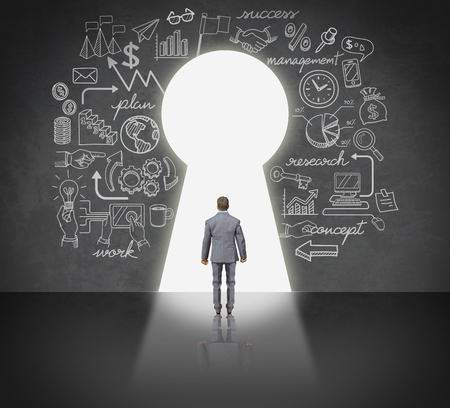 Business man standing front key hole door.の写真素材