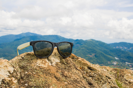 The old sunglasses , placed on the stone.The background is a mountain and the skyの写真素材