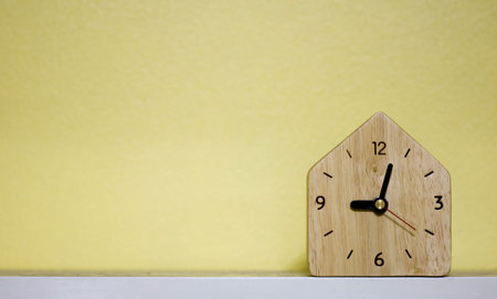 Wooden clock On the white table and yellow background with copy spaceの写真素材