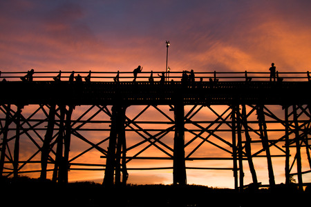 Silhouette of old wooden bridge at Sangklaburi in Thailand,sunsetの写真素材