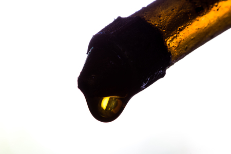 Close-up  Old gas nozzle with Yellow Gold Oil drop on white background  with copy spaceの写真素材