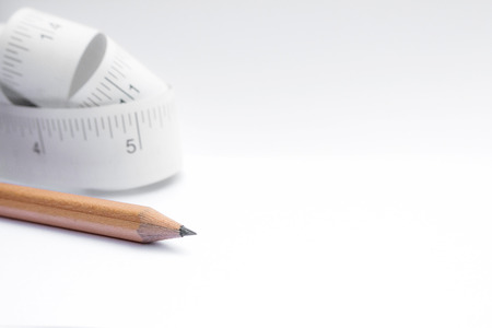 Close-up Pencil and paper measuring tape roll  on white background with copy spaceの写真素材