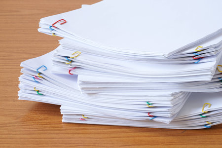 Pile of documents with colourful clips on the wood table.