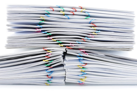 Colorful heart-shaped paperclip on top of pile overload paperwork place on white background.