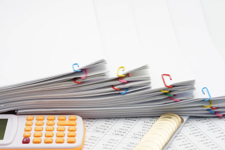 Step pile overload paperwork of report with colorful paperclip and pile of gold coins with calculator on finance account.の写真素材