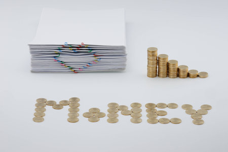 Pile document with colorful heart-shaped paperclip and step pile of gold coins on white background.の写真素材