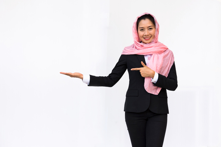 Empty hand holding of smiling woman in black suit wearing pink turban on white background.の写真素材