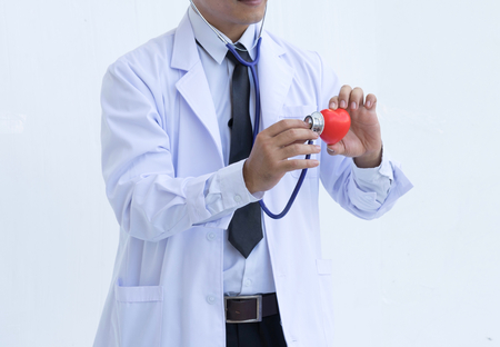 Closeup male doctor with red heart and stethoscope on white background.の写真素材