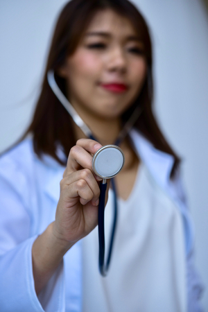 Blur smiling young woman doctor closeup of hands with stethoscrop on white background.の写真素材
