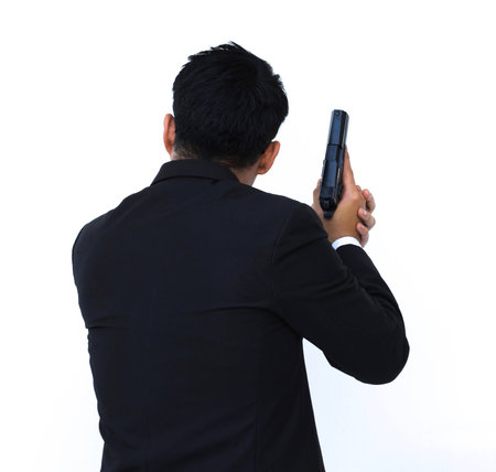 Handsome businessman in suit holding a gun on white background.の写真素材