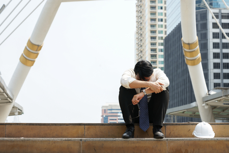 Tired or stressful businessman sitting sadly on the stairs after working on the building background.の写真素材
