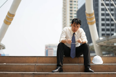 Tired or stressful businessman sit on the stairs after working on the building background.の写真素材