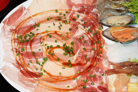 mix Pork slice and seafood platter set served on big white plate dish top with rich soya sauce for Shabu or Sukiyaki Japanese hot pot styleの写真素材