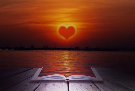 Heart's sunset with open book on wood stage backgroundの写真素材