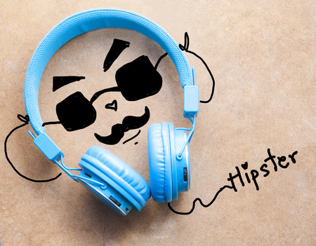 Blue headphones with hipster man listening music on wooden backgroundの写真素材