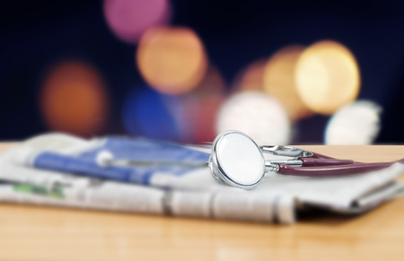 Stethoscope on doctor table with newspaper and outdoor backgroundの写真素材