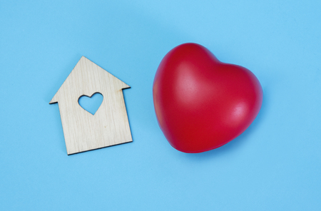 Red heart and wooden home isolated on light blue backgroundの写真素材