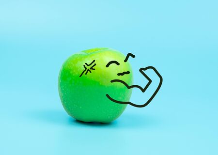 Strong cartoon character on green apple isolated on blue pastel background, healthy   or diet conceptの写真素材