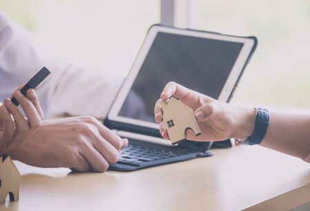 Hand holding little home model for new village estate, love and family conceptの写真素材