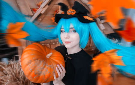Pretty young girl witch halloween costume portrait dressed in black with pumpkinsの写真素材