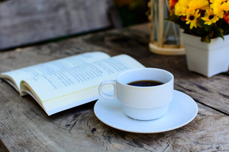 a cup of coffee on wooden table and bookの写真素材