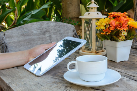 a cup of coffee and tablet on wood floor with flower