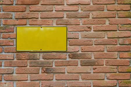 Yellow metal plate on brick wallの写真素材