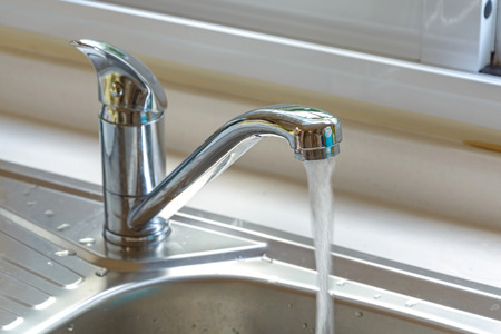 Kitchen faucet with a flowing waterの写真素材