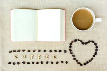 Blank notebook with cup of coffee and beansの写真素材
