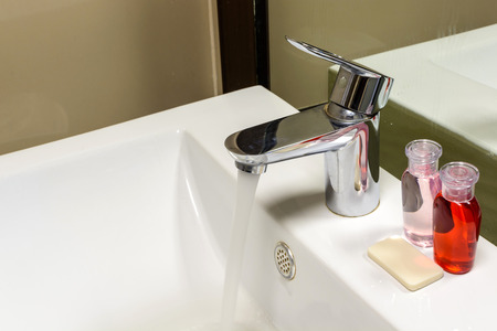 Close up of faucet with a flowing water in toiletの写真素材